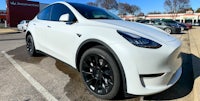 a white tesla model y parked in a parking lot