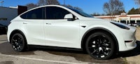 a white tesla model y parked in a parking lot